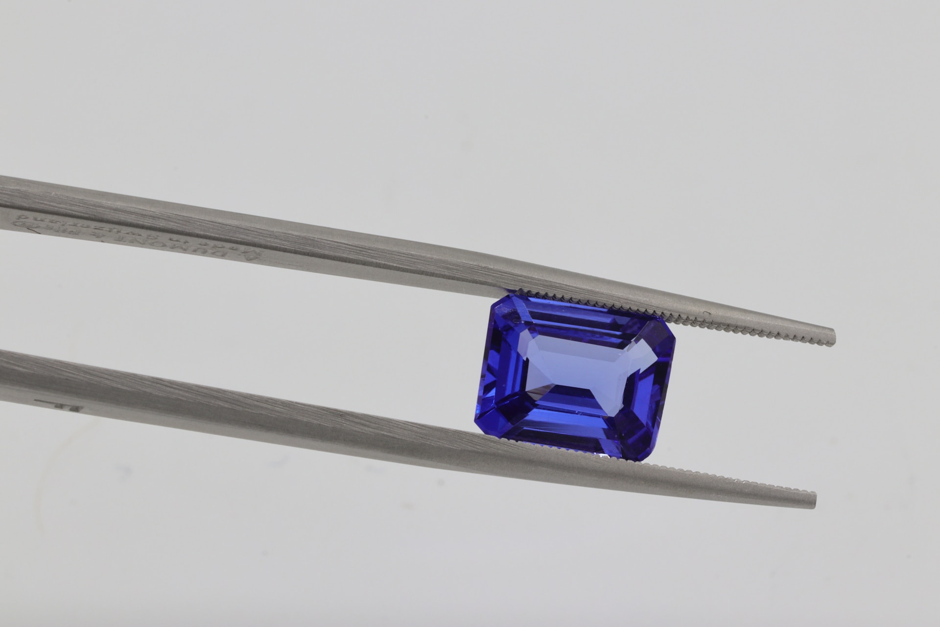 A tanzanite held in gemstone tweezers
